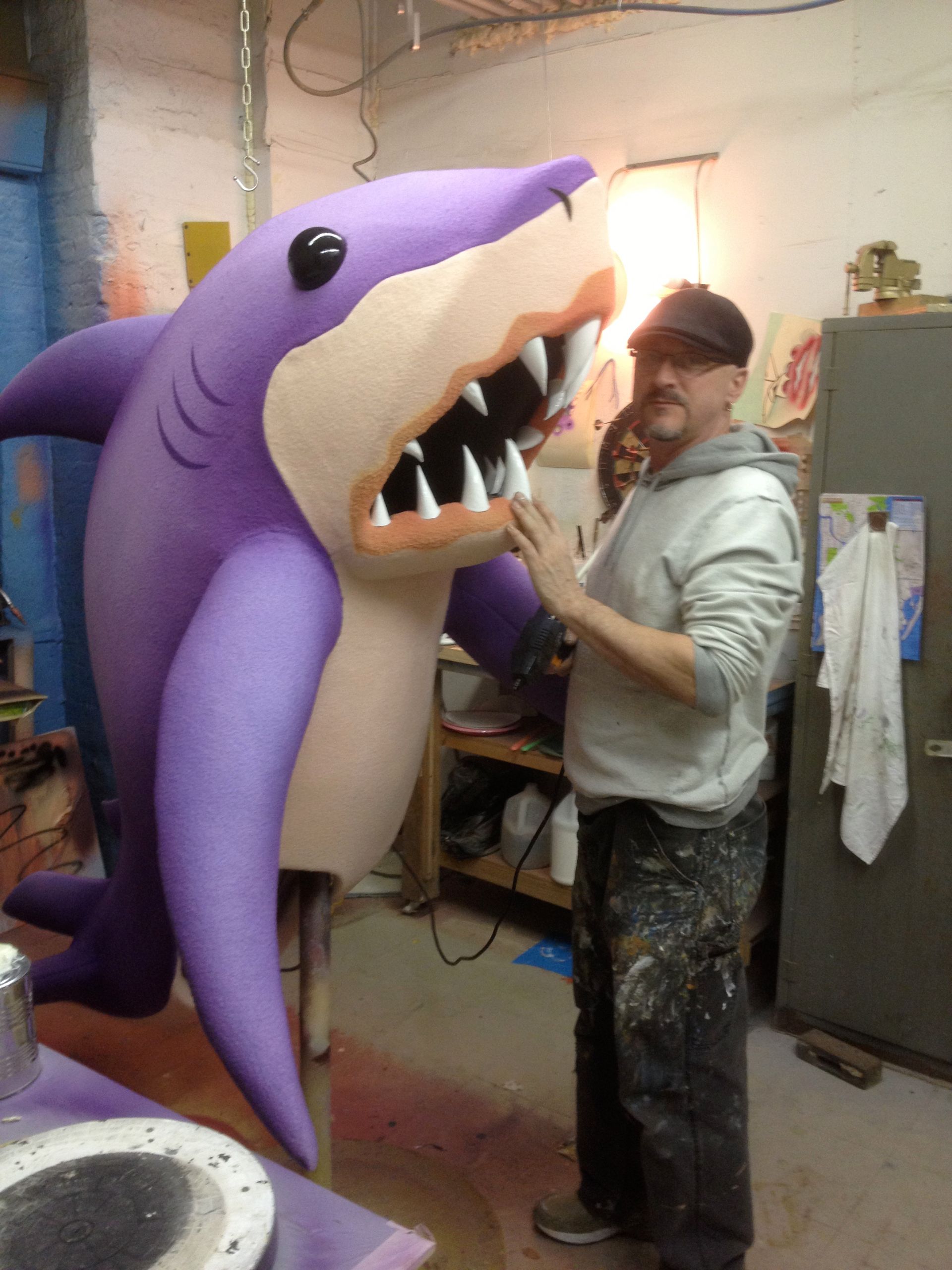 A man standing next to a giant purple shark