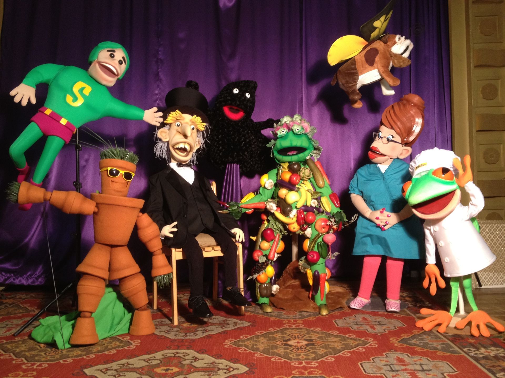 A group of puppets with one wearing a green shirt with the letter s on it