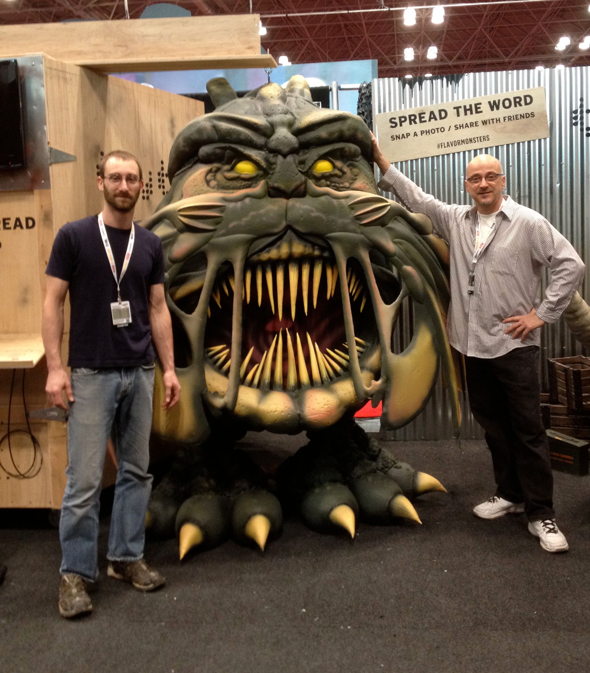 Two men standing next to a monster with a sign that says spread the word