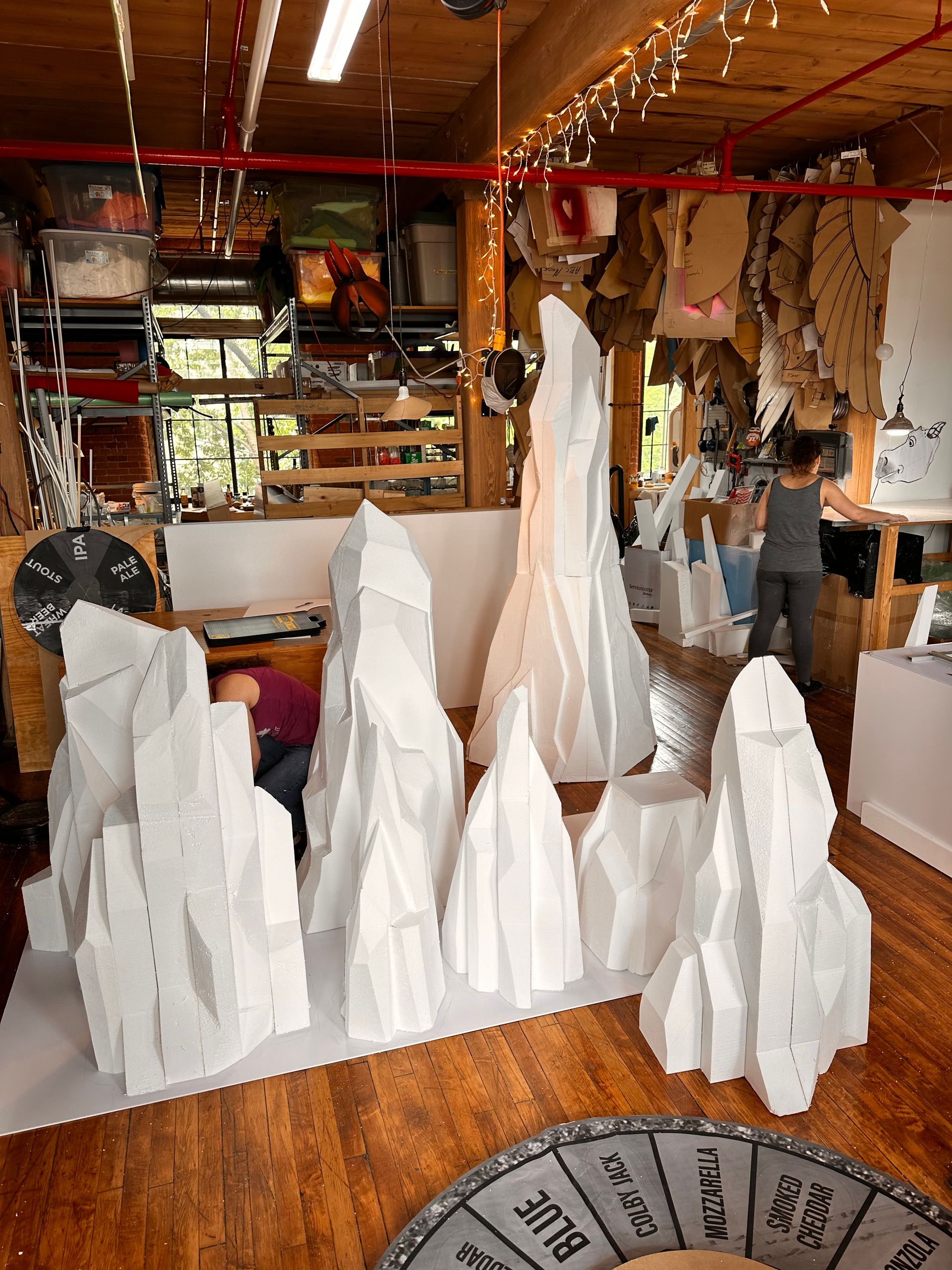 White paper sculptures resembling mountain peaks in a studio, with people working.