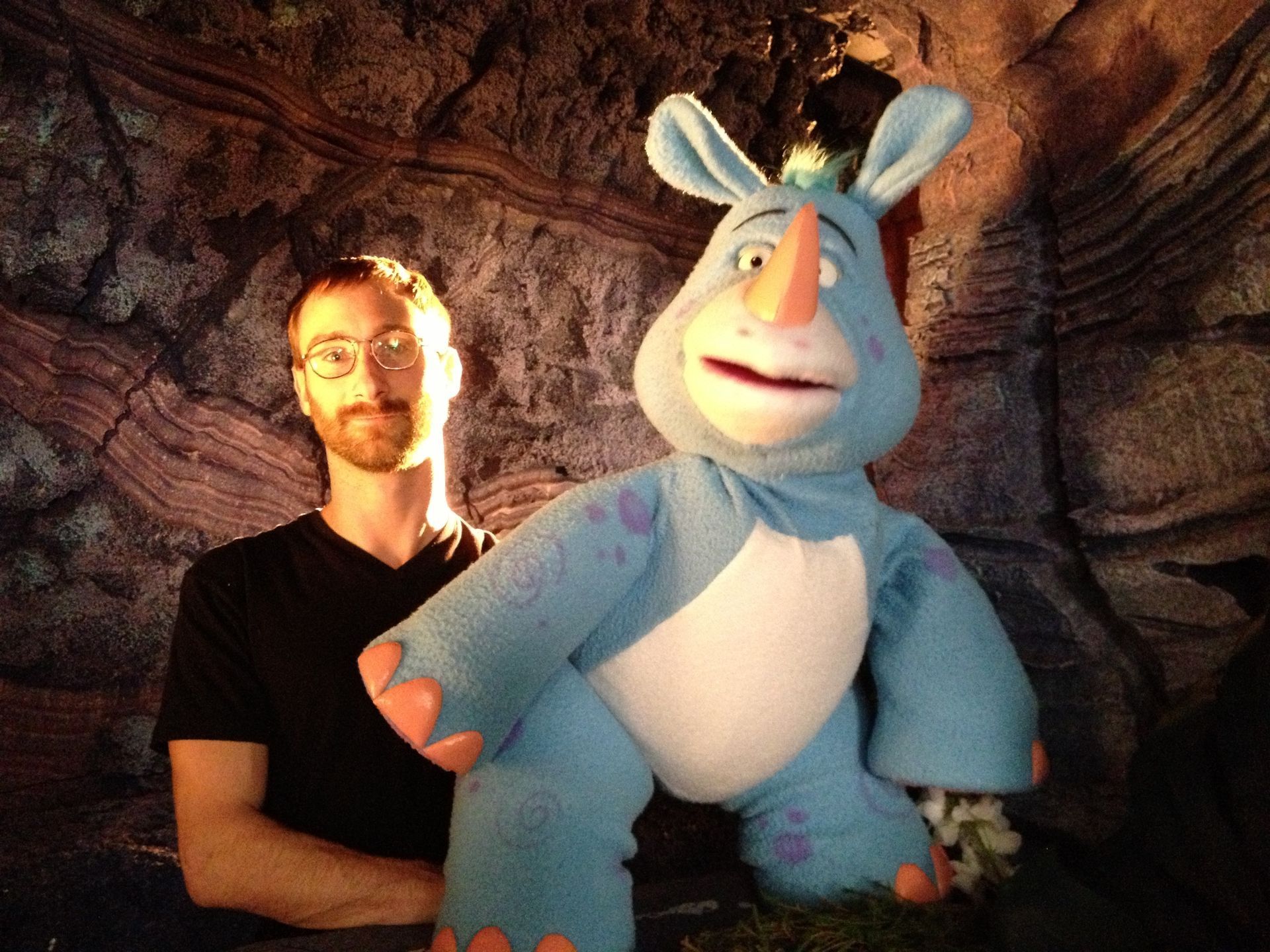 A man standing next to a blue stuffed rhino