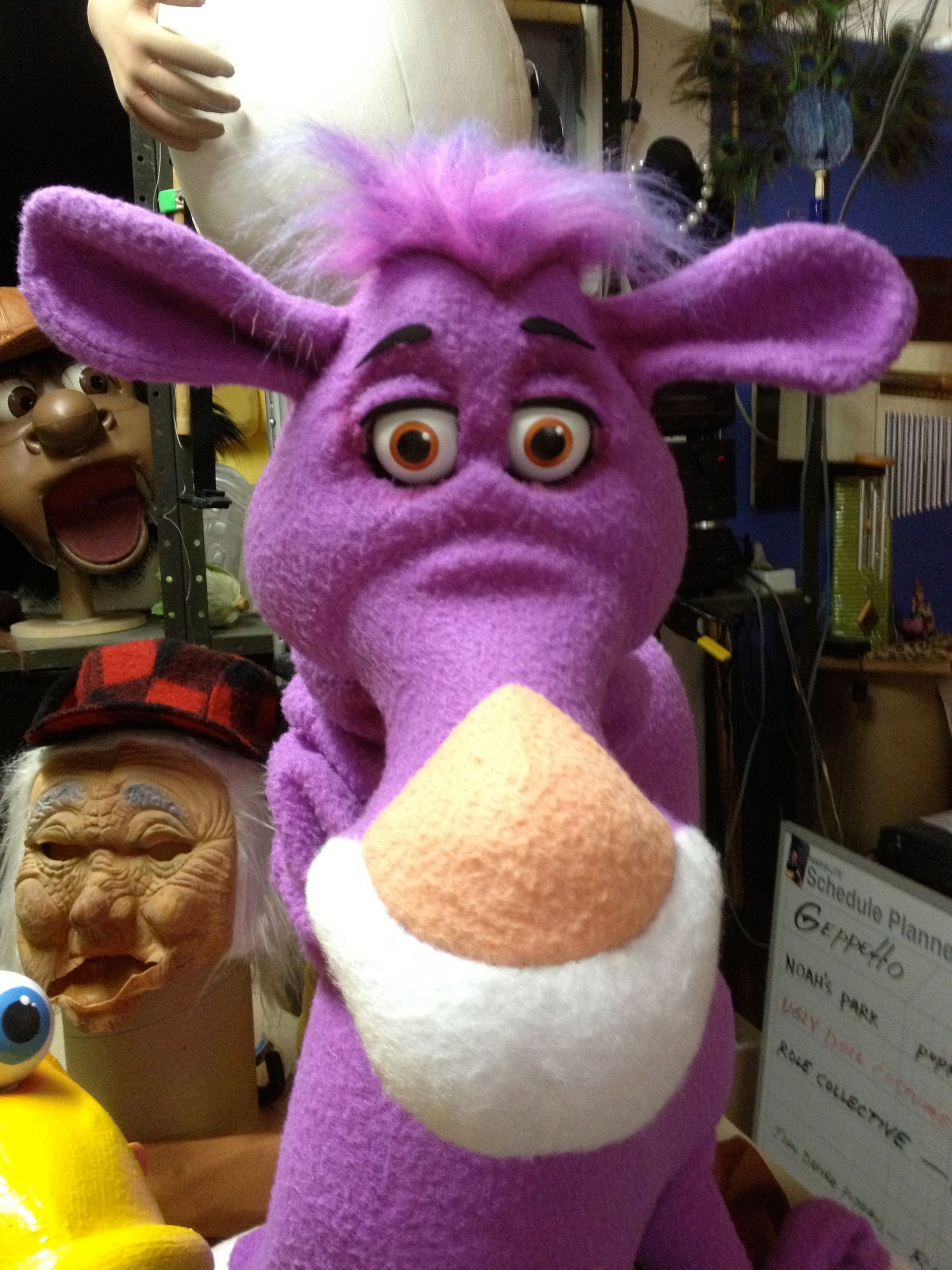 A purple stuffed animal with big eyes and a white nose