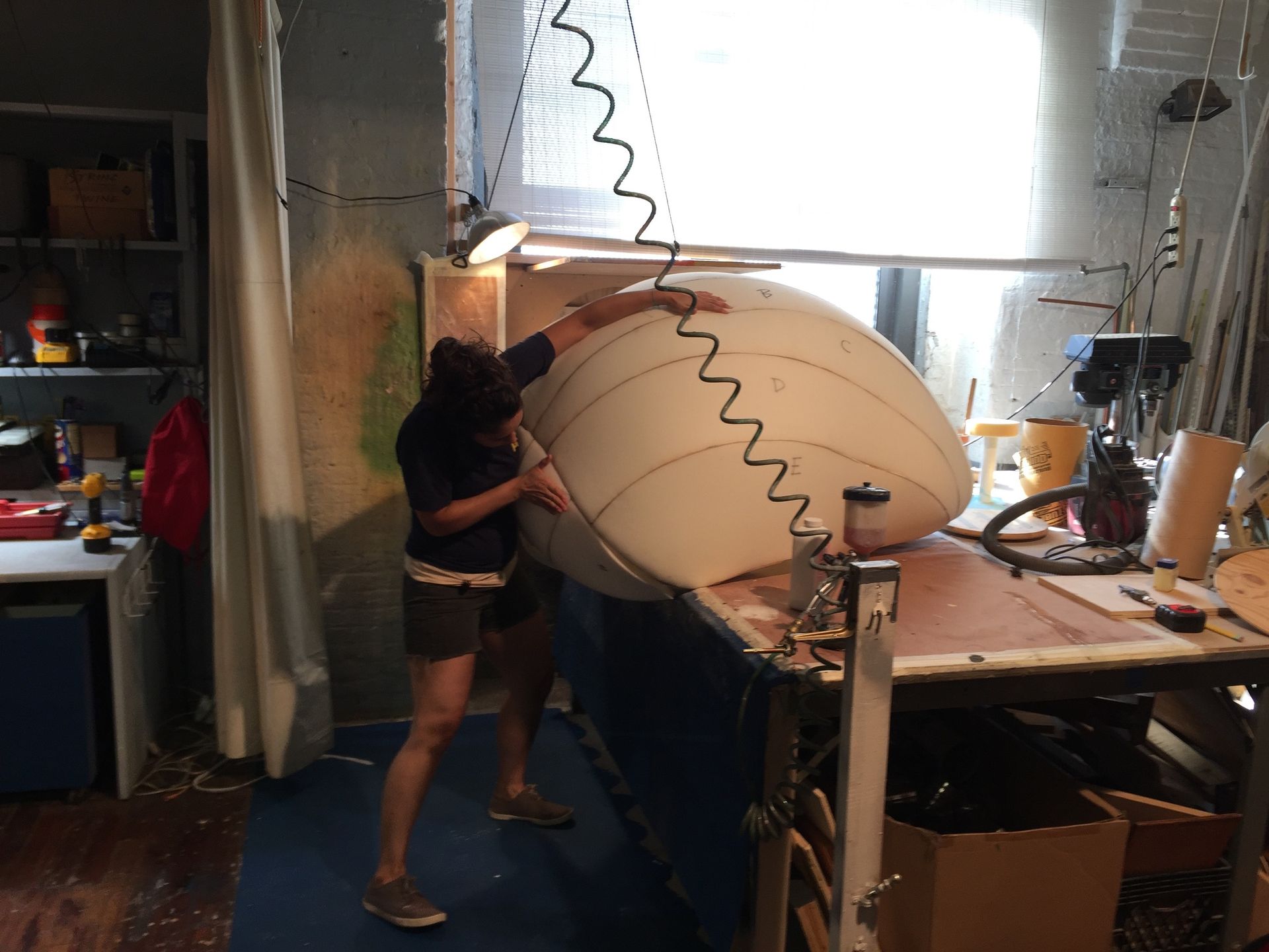 A woman is working on a large foam ball in a workshop