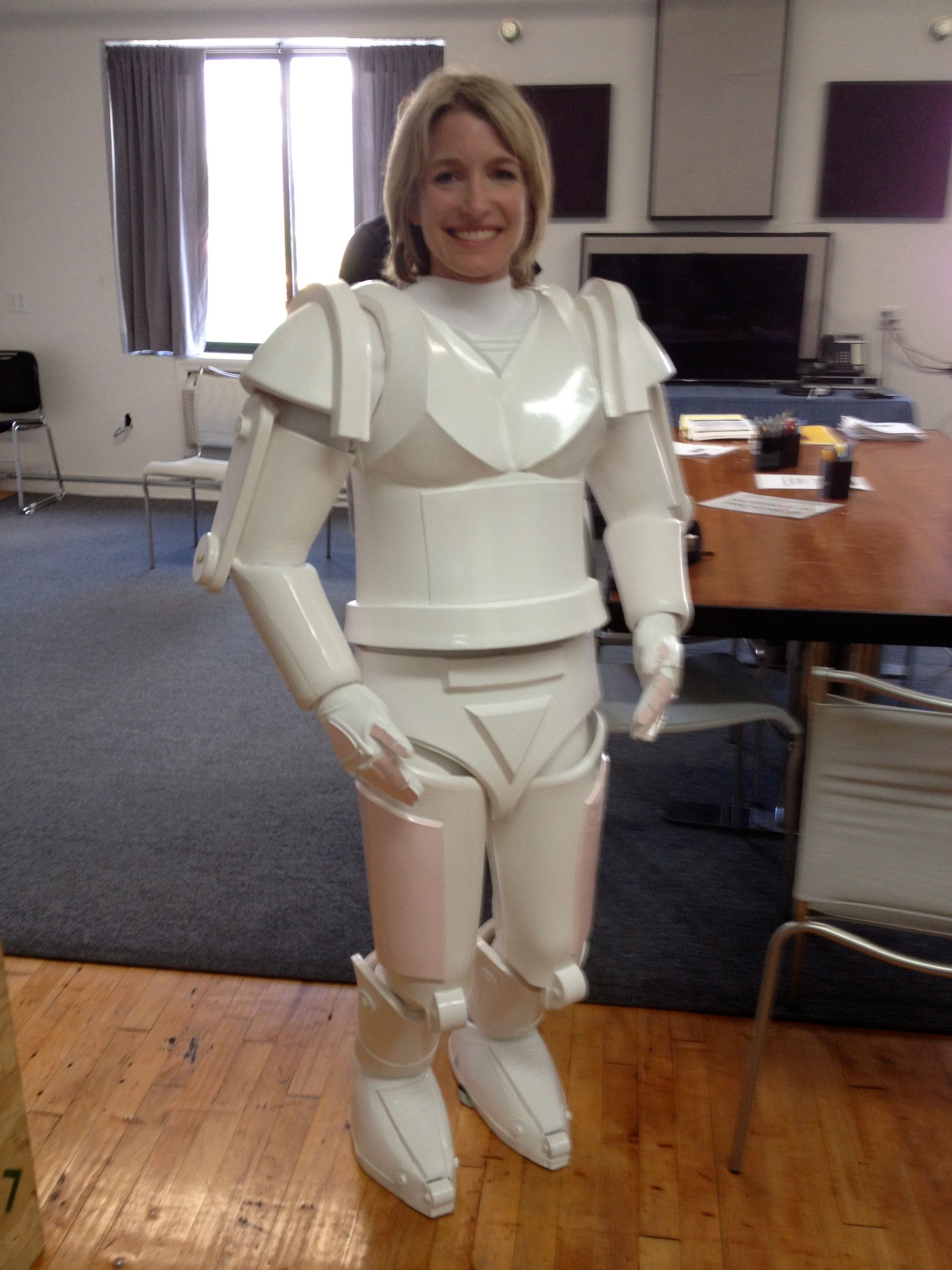 A woman is wearing a white armored suit and smiling