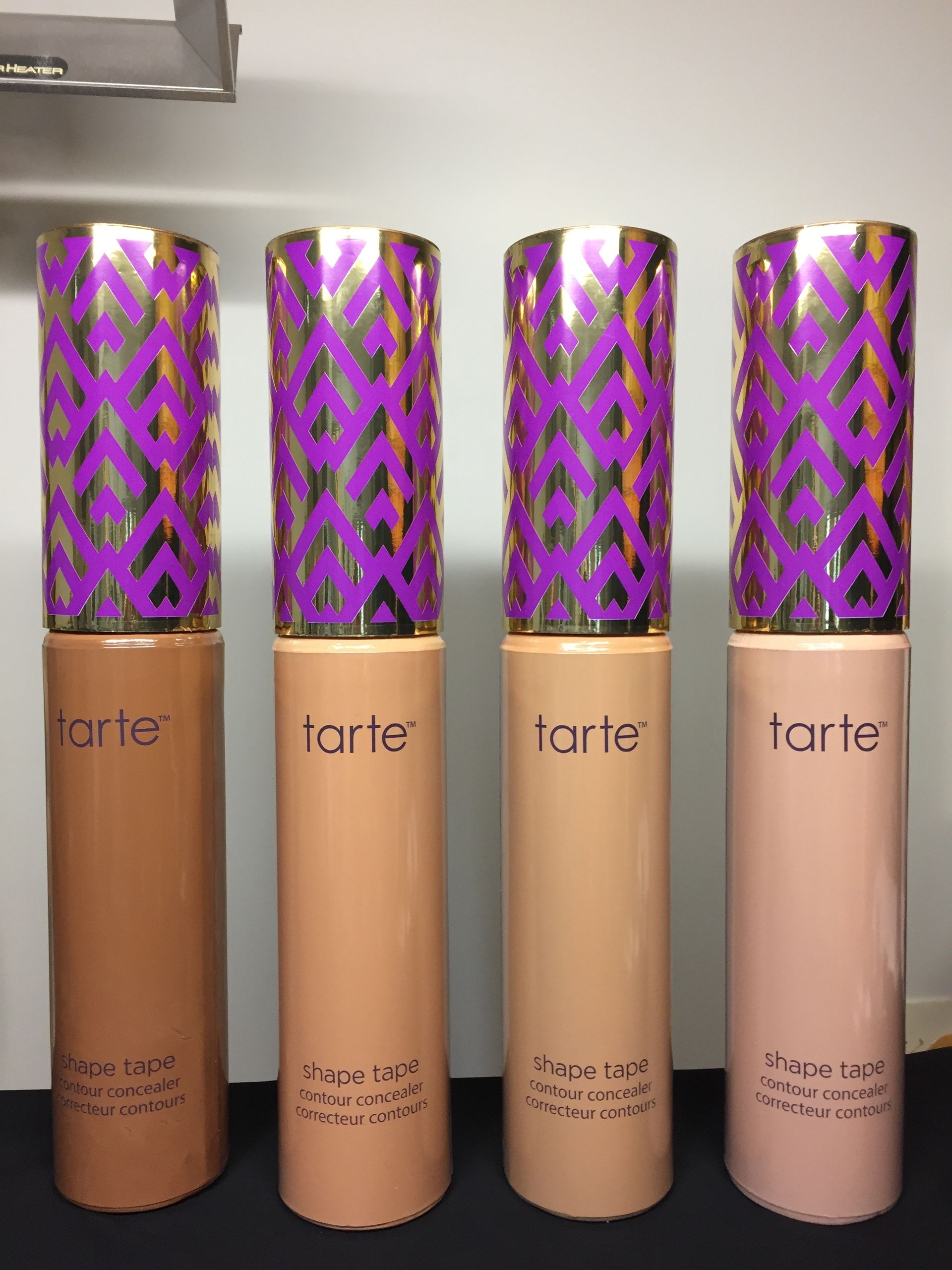 Four bottles of tarte cosmetics are lined up on a table.