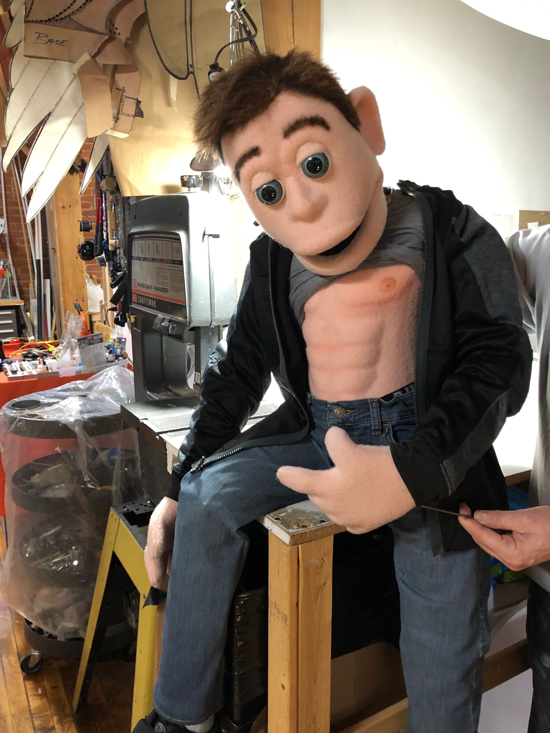 A man in a puppet costume is sitting on a wooden ladder