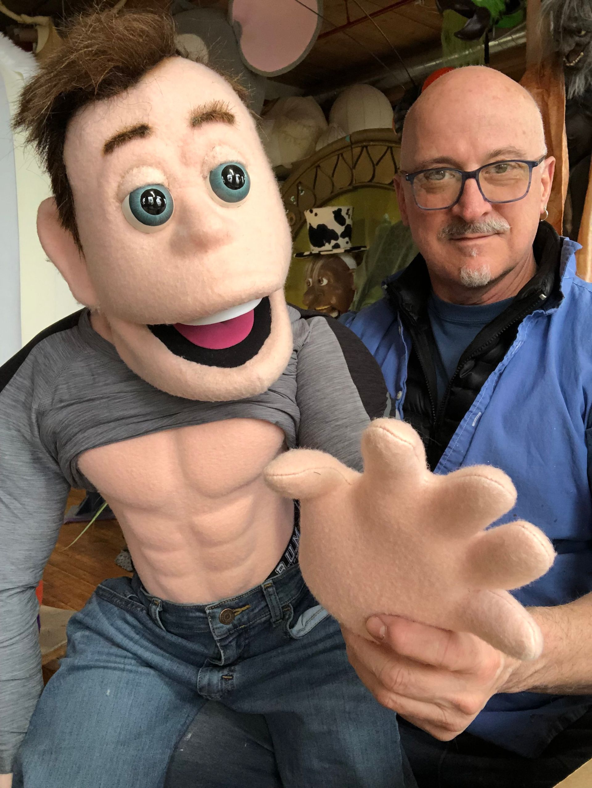 A man is holding a puppet with his shirt off