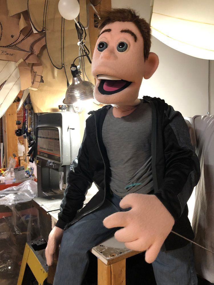 A puppet of a man is sitting on a wooden stool