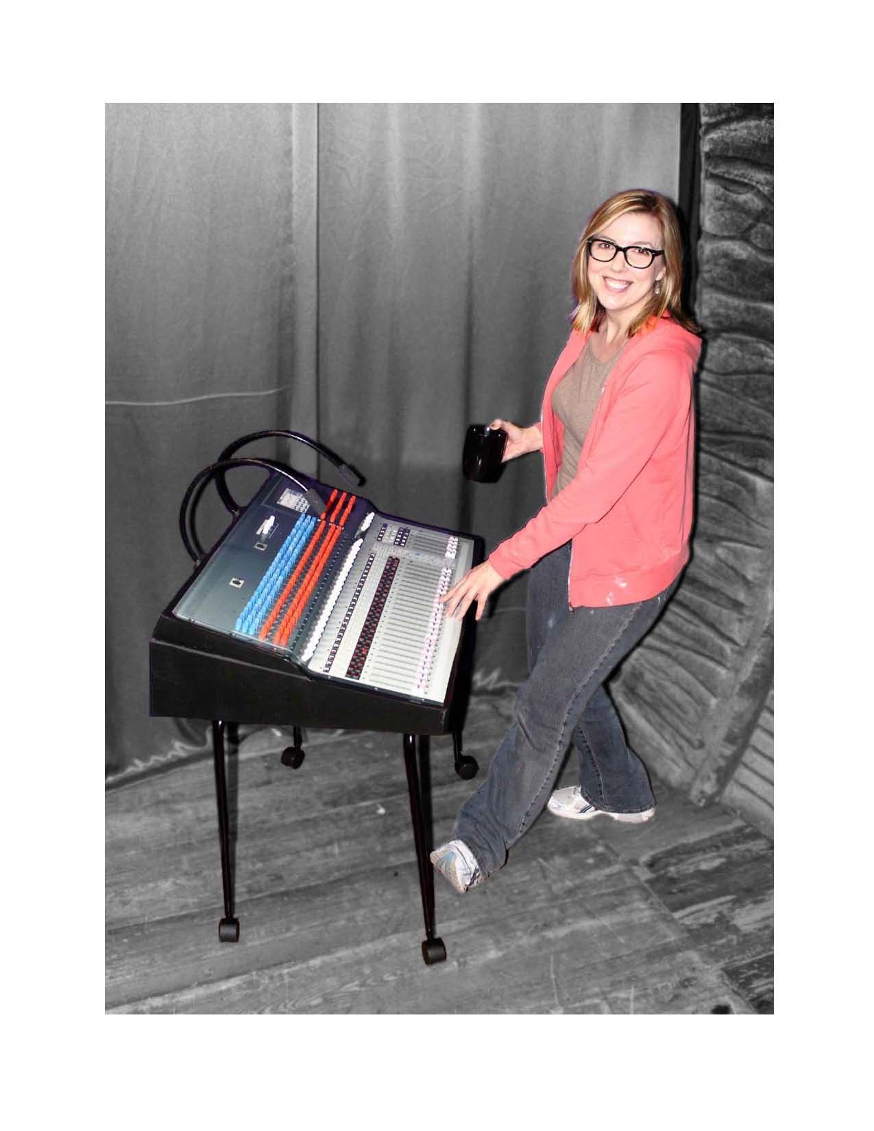 A woman in a red jacket is standing next to a keyboard.