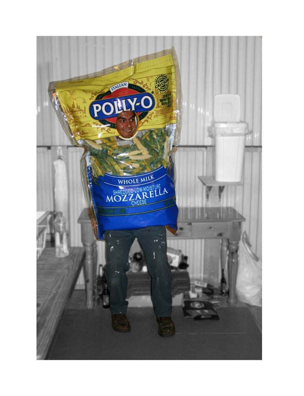 A man is standing in front of a table holding a bag of mozzarella cheese.