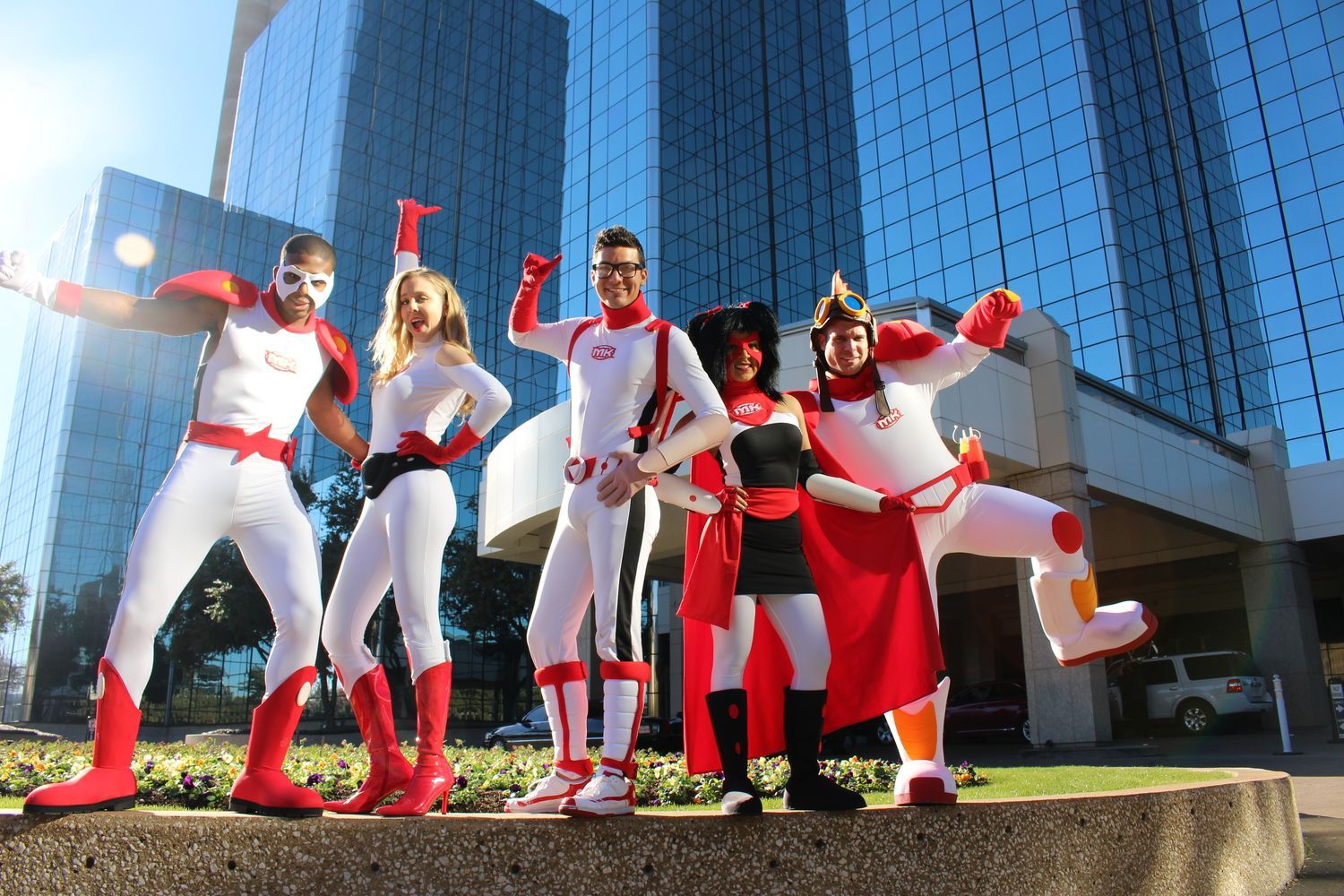 A group of people in superhero costumes are posing for a picture in front of a building.