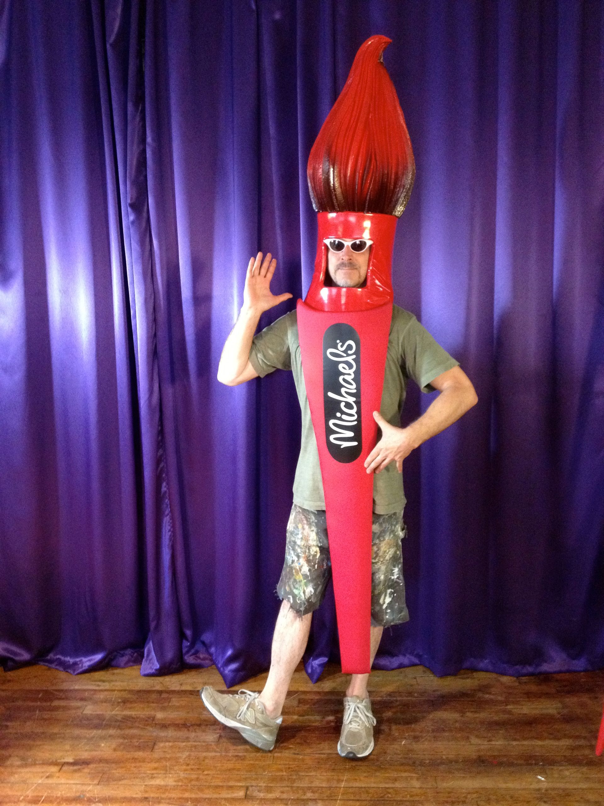 A man in a michaels costume stands in front of a purple curtain