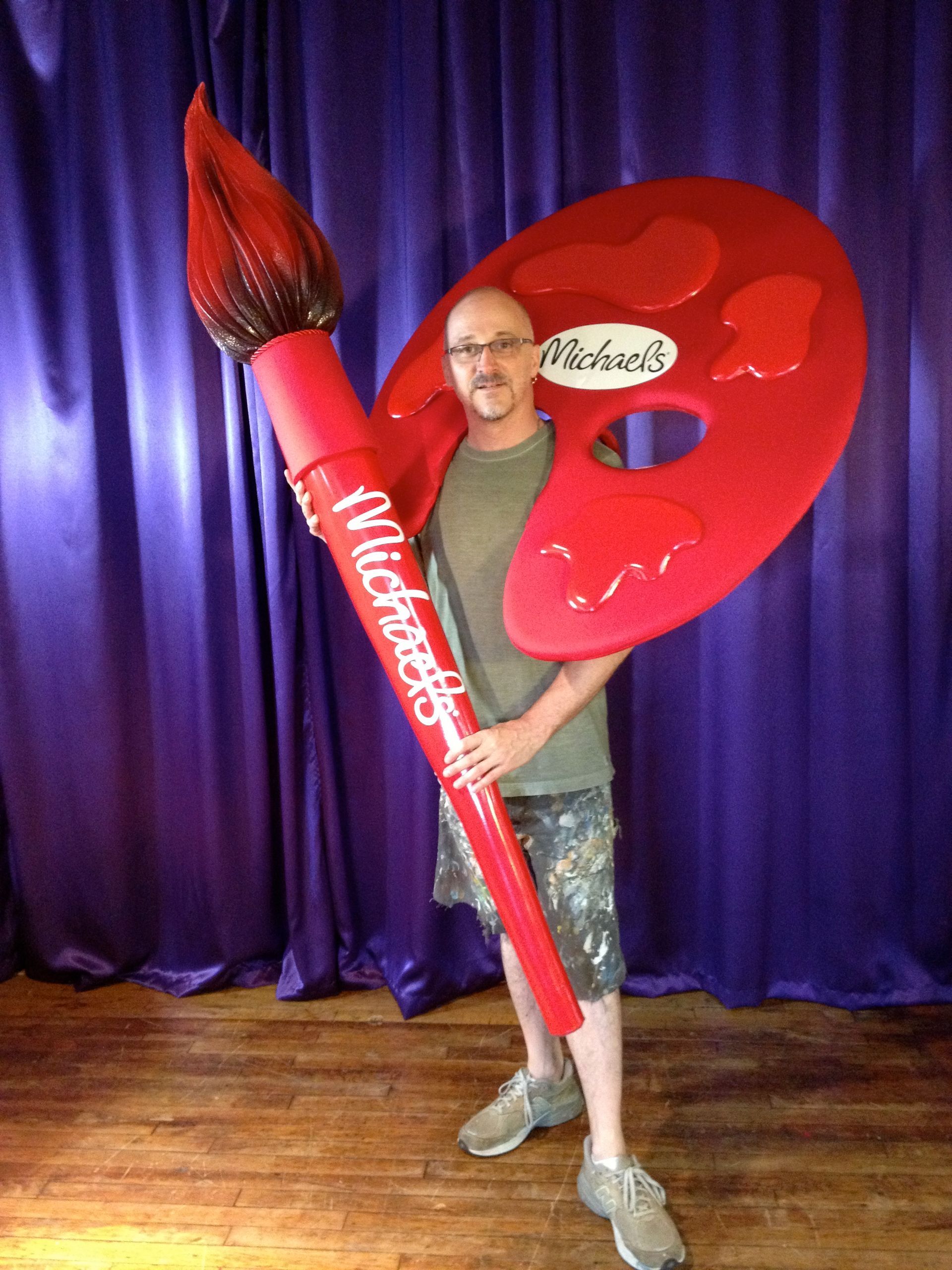 A man holding a large brush and a palette with wildflowers written on it