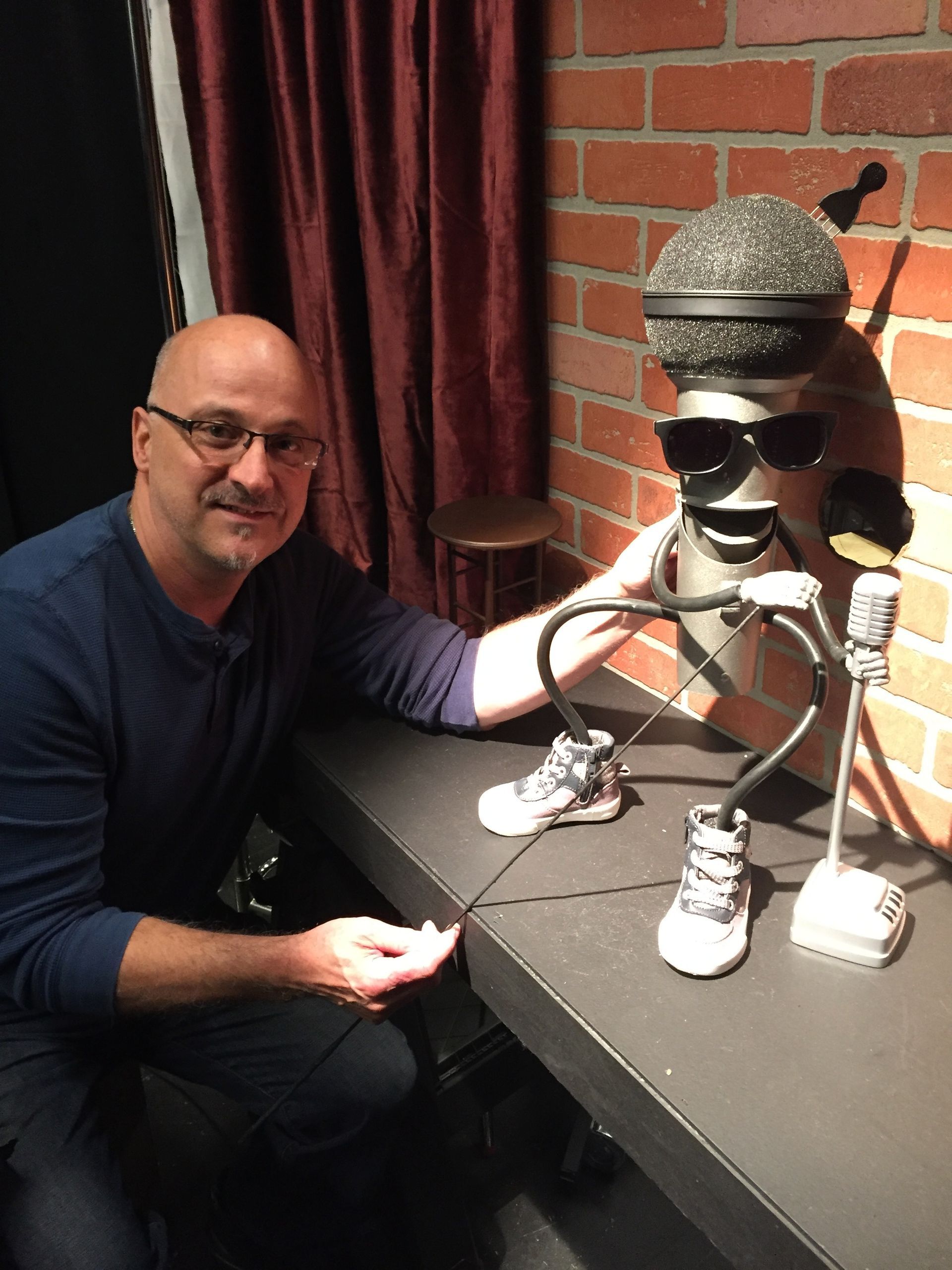 A man is sitting in front of a statue of a man with a microphone on his head.
