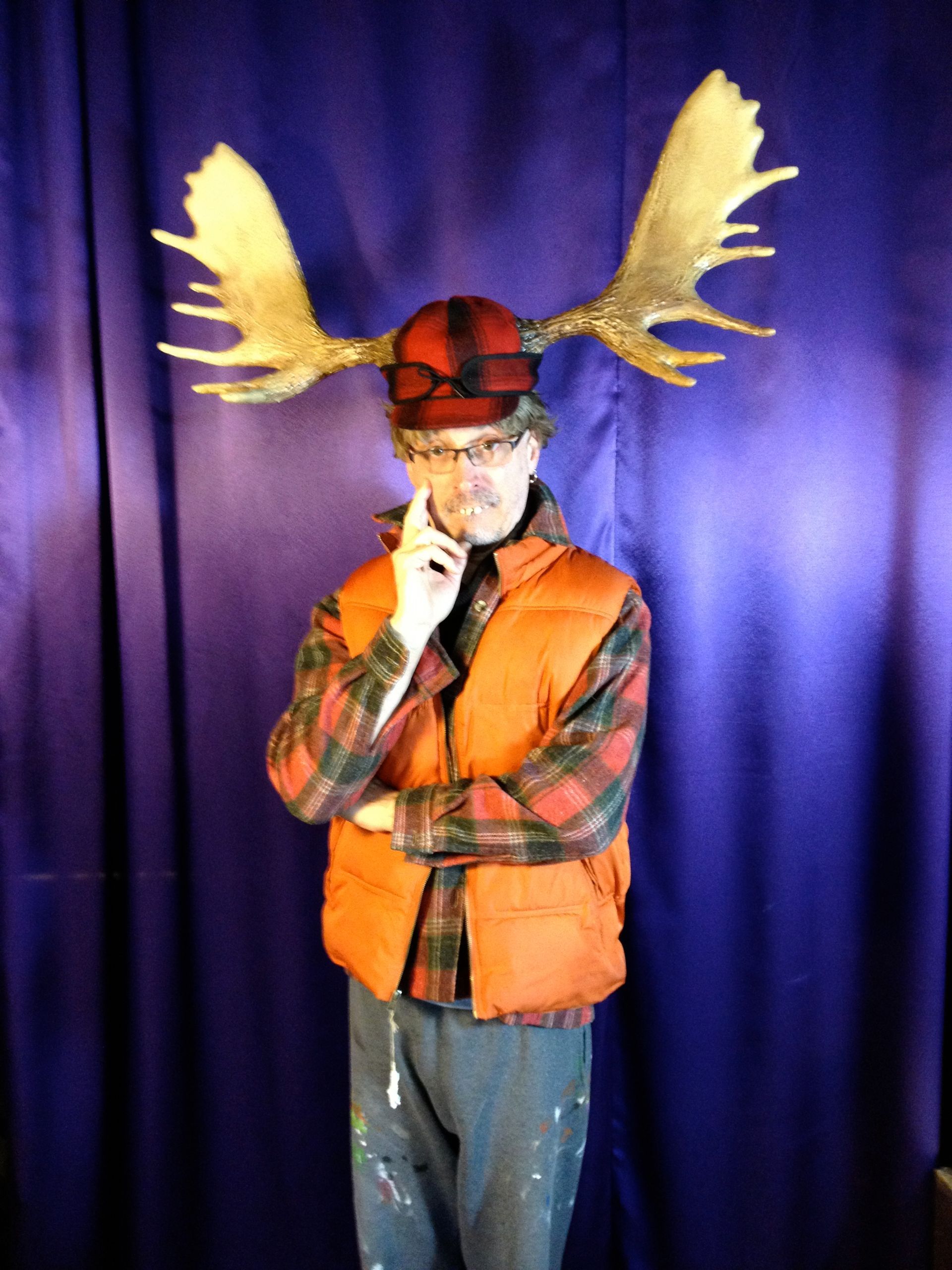 A man wearing a moose hat and an orange vest