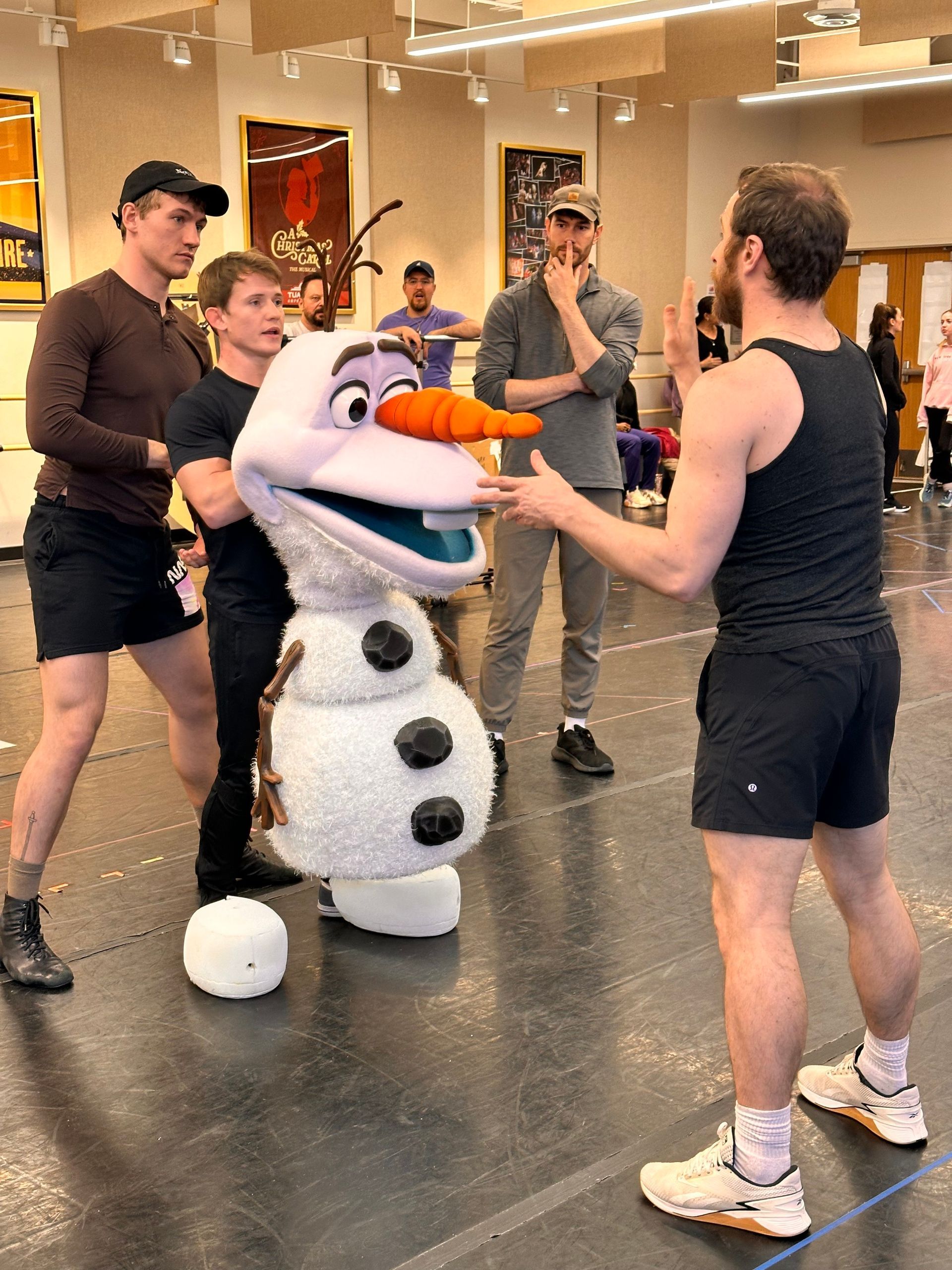 A group of men are standing around a stuffed snowman.