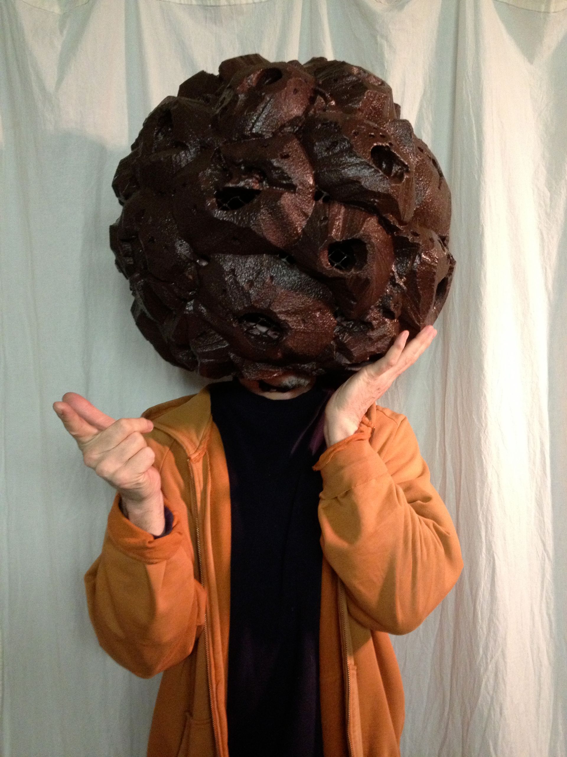 A person wearing a brown jacket has a large brown ball on their head