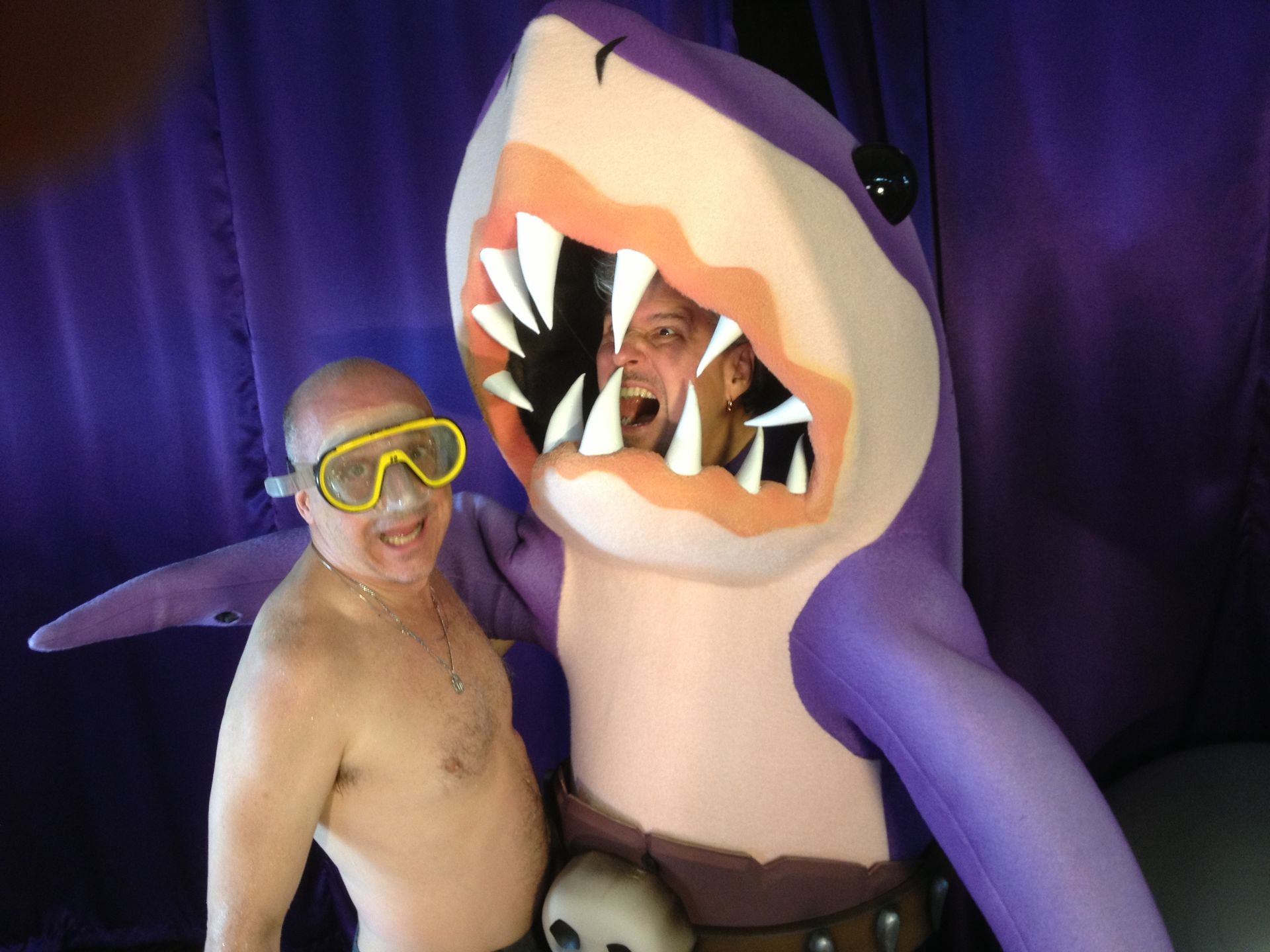 A man wearing goggles stands next to a purple shark