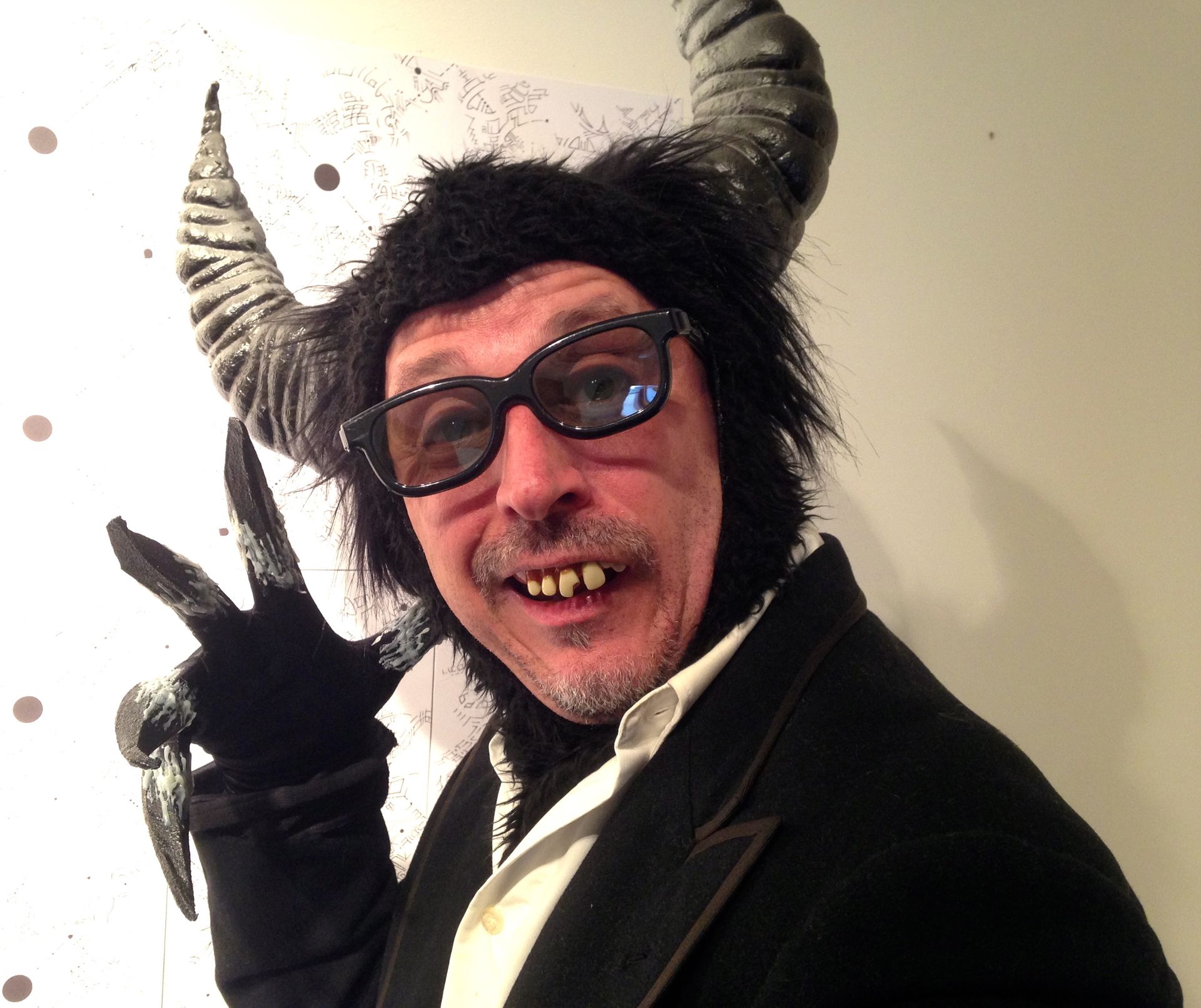 A man wearing a devil costume with horns and glasses