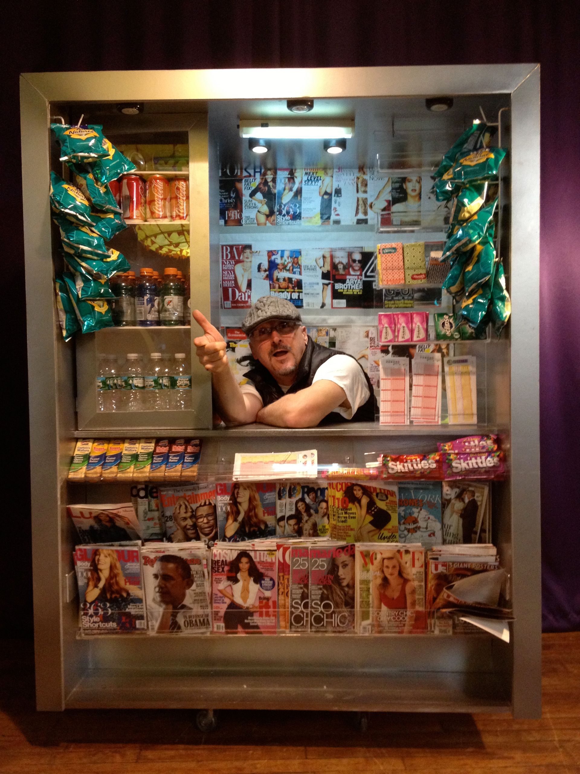 A man is standing in front of a vending machine filled with magazines.