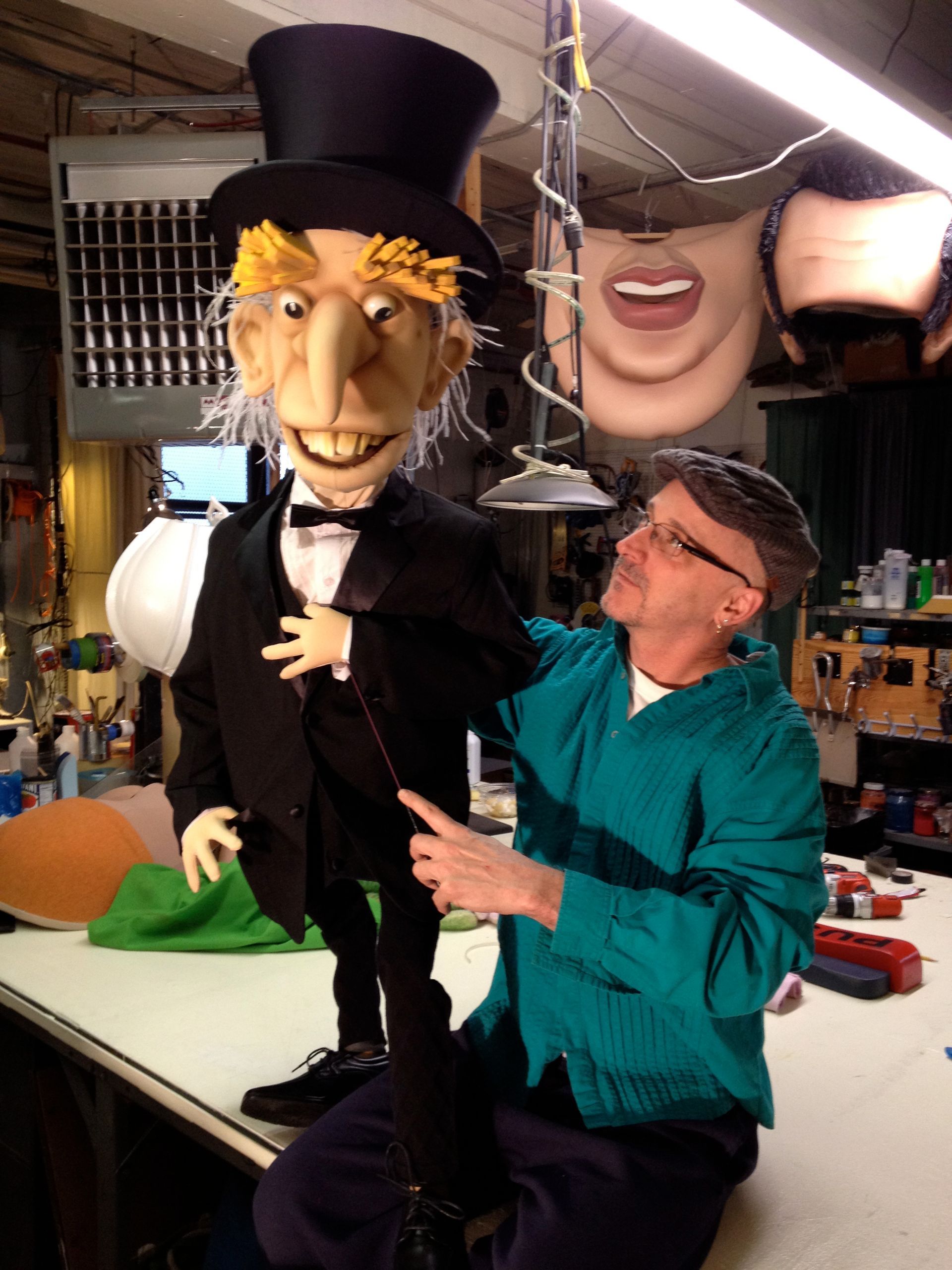 A man sitting next to a puppet wearing a top hat