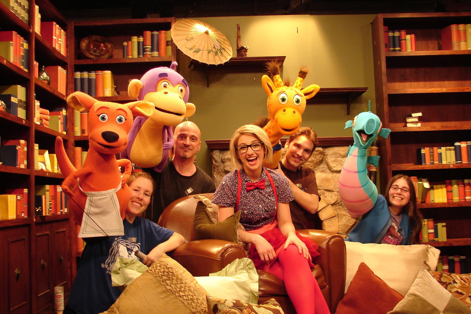 A group of people sitting on a couch with stuffed animals around them