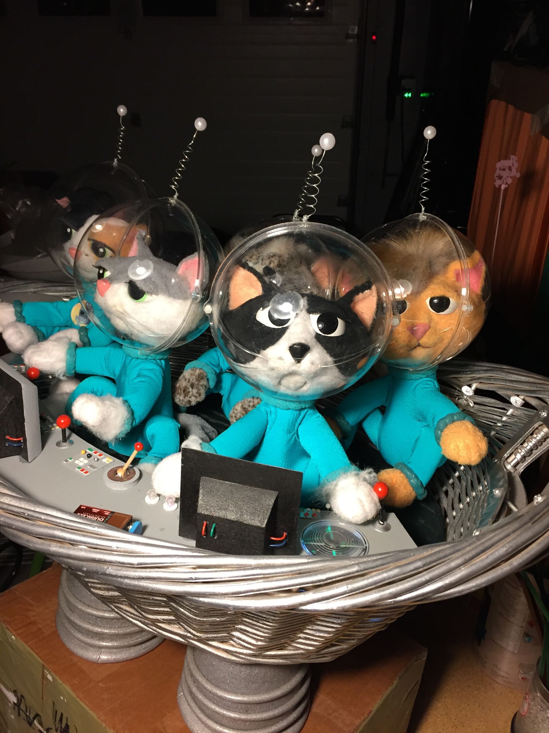 A group of stuffed animals in space suits are sitting in a basket.
