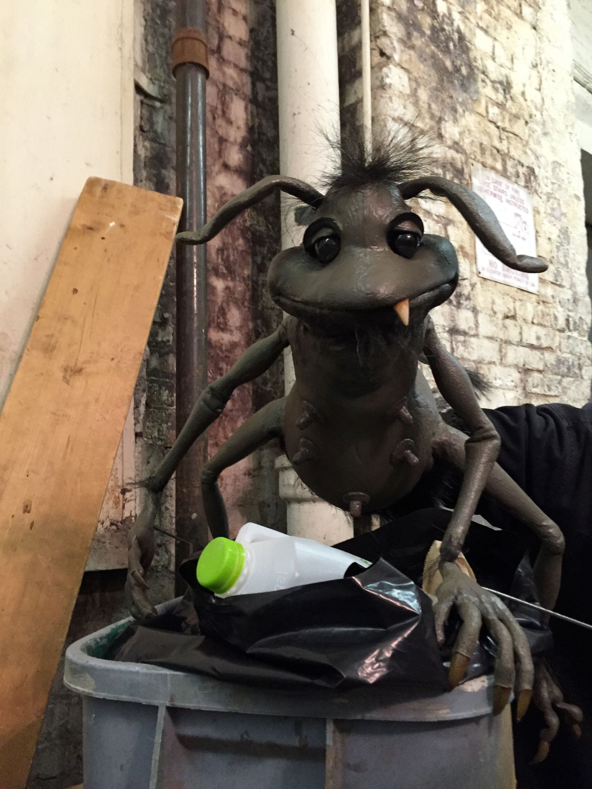 A stuffed ant is sitting on top of a trash can