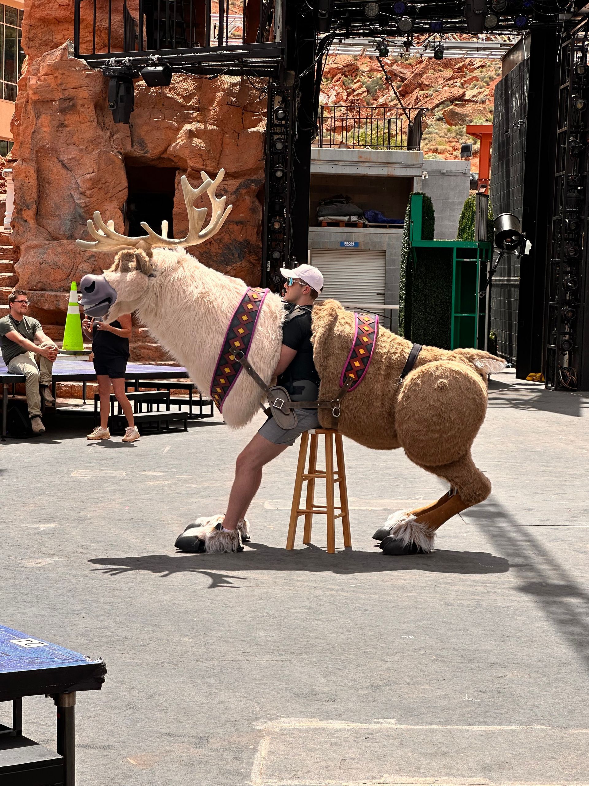 A man is riding on the back of a stuffed reindeer