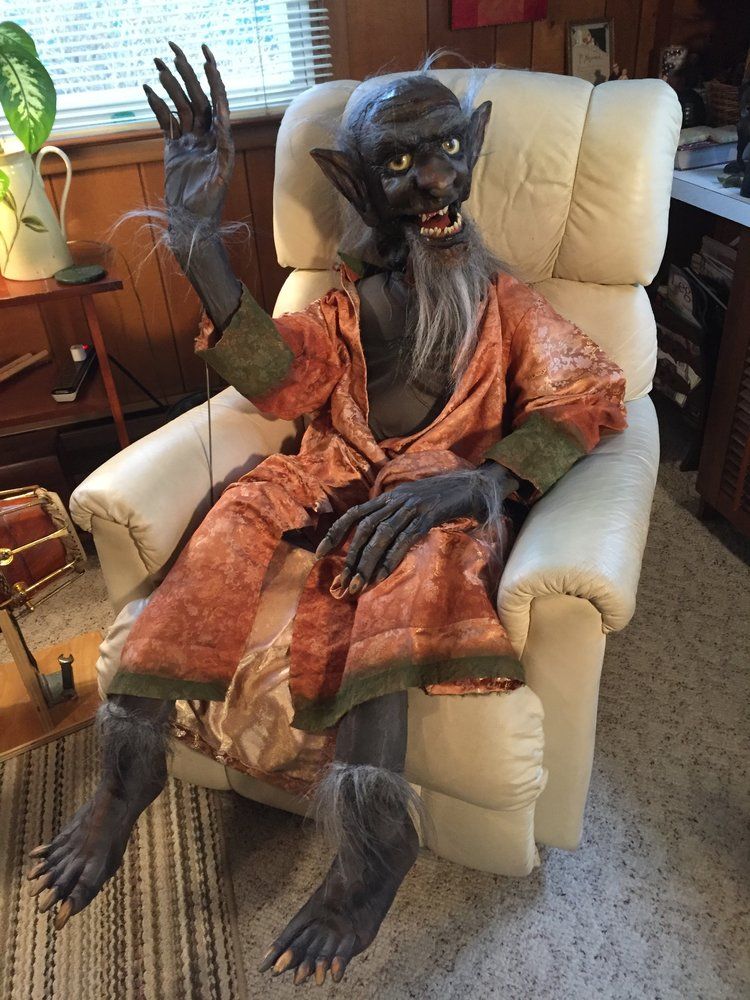 A statue of a monster is sitting in a recliner in a living room.