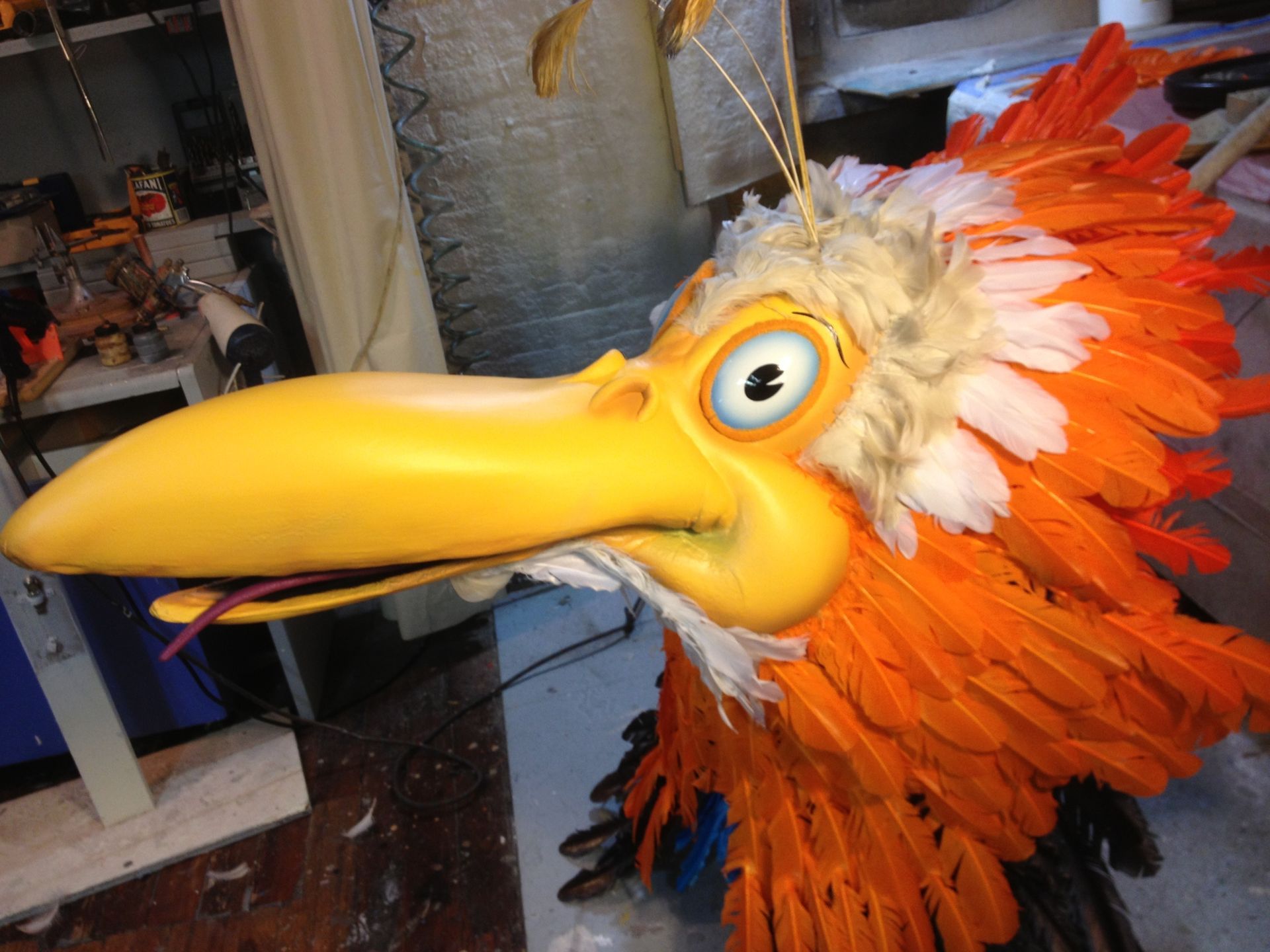 A cartoon bird with a yellow head and orange feathers is sitting on a table.