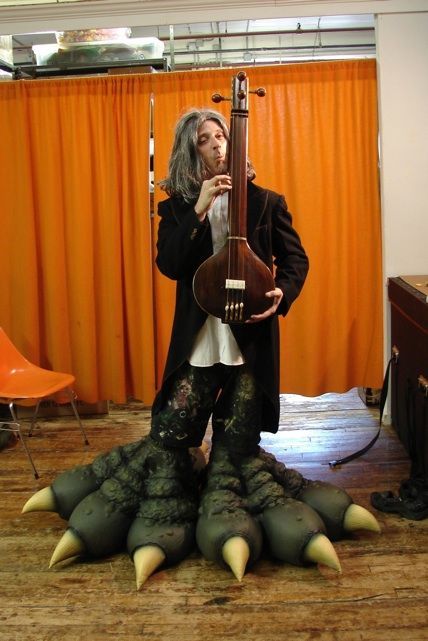 A man in a monster costume is playing a guitar