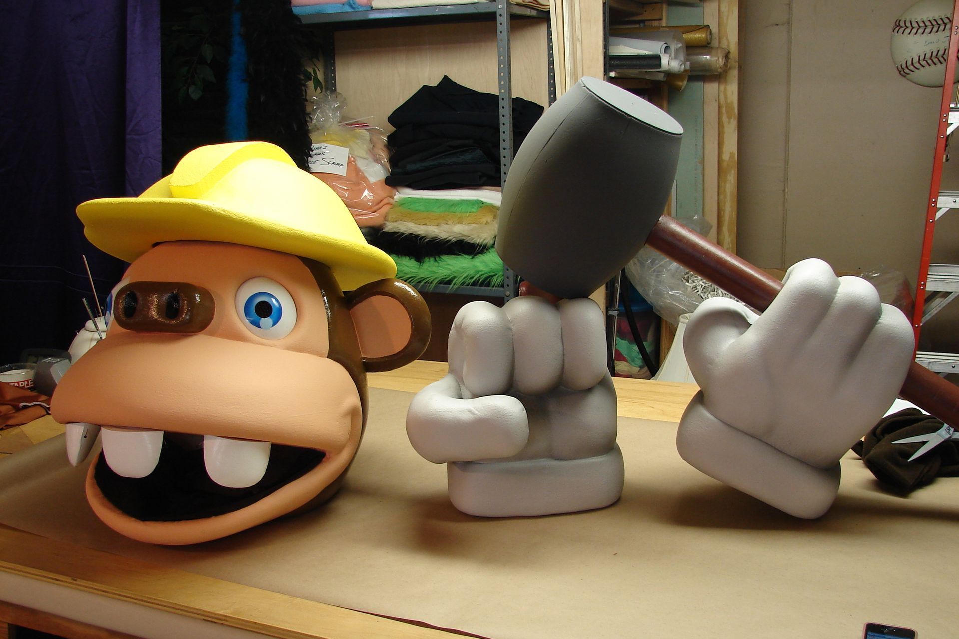 A monkey with a yellow hat is holding a hammer