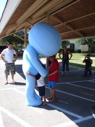 A group of people standing around a blue inflatable man
