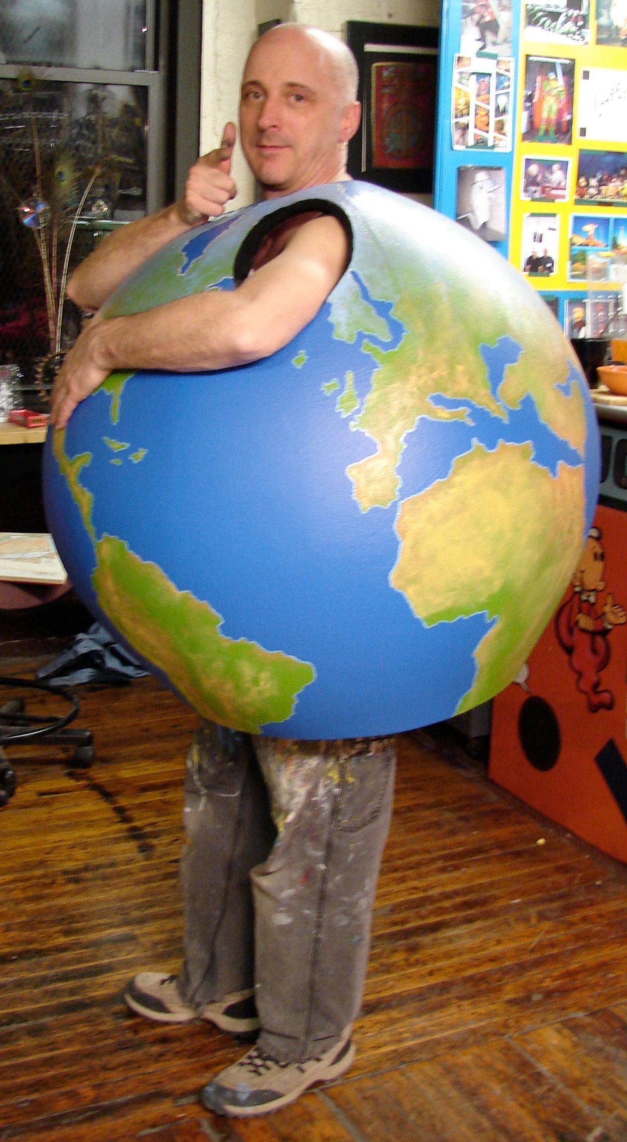 A man in a globe costume is giving a thumbs up