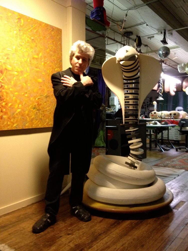 A man in a suit is standing next to a statue of a cobra.