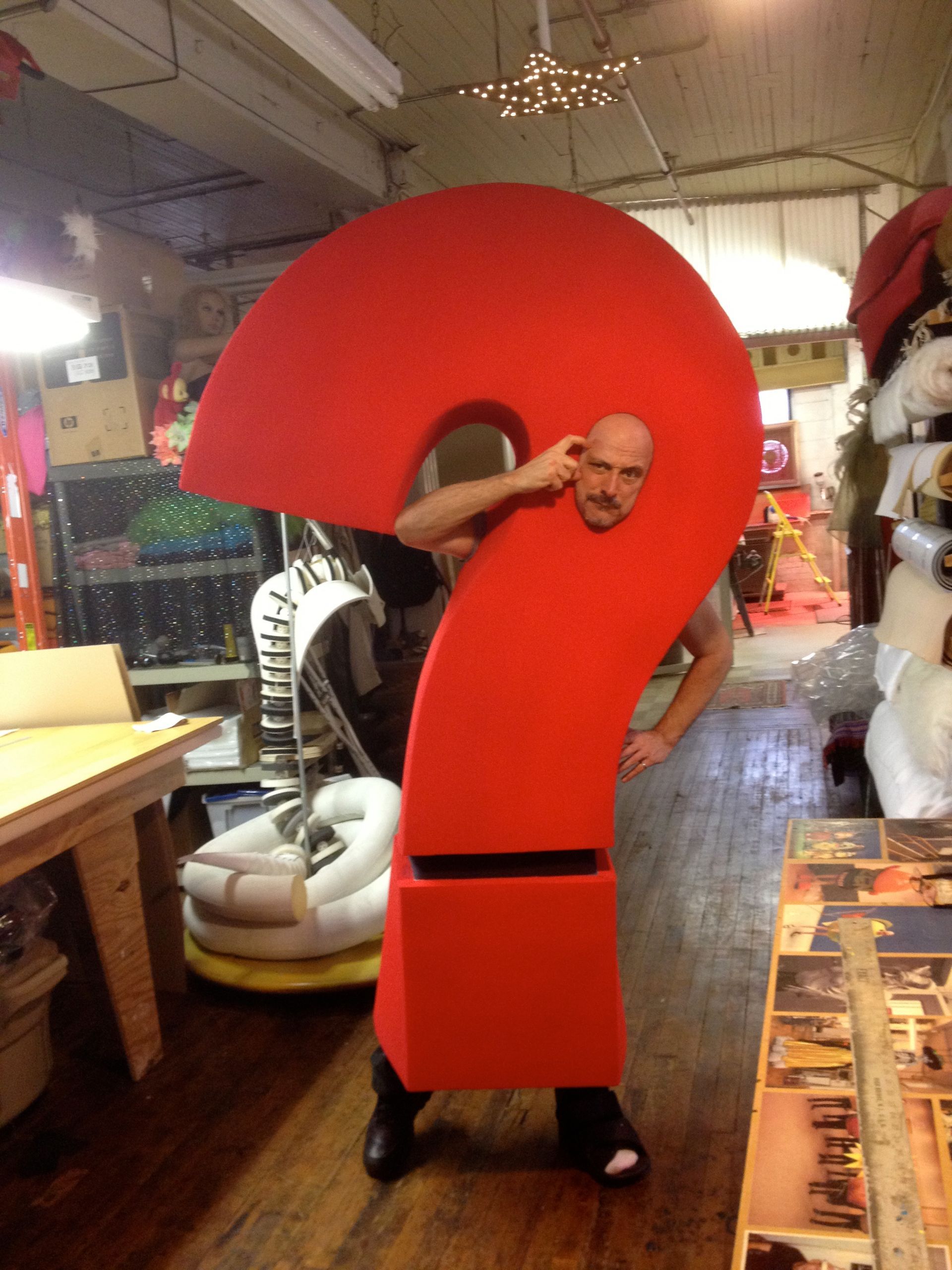 A man is dressed in a red question mark costume
