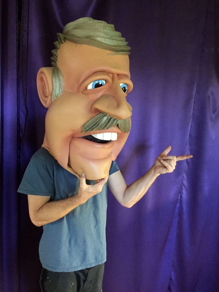 A man in a blue shirt is wearing a large cartoon head
