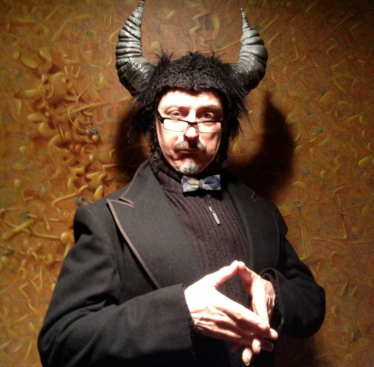 A man wearing a devil costume with horns and glasses