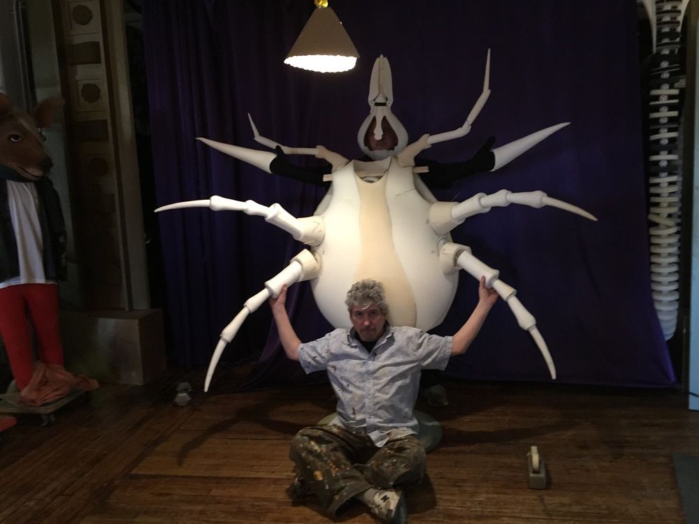 A man is kneeling down in front of a giant spider statue