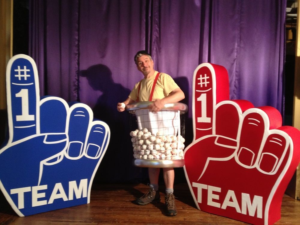 A man is standing next to two foam hands that say team