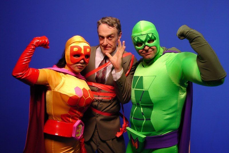 A man and two women dressed as superheroes are posing for a picture