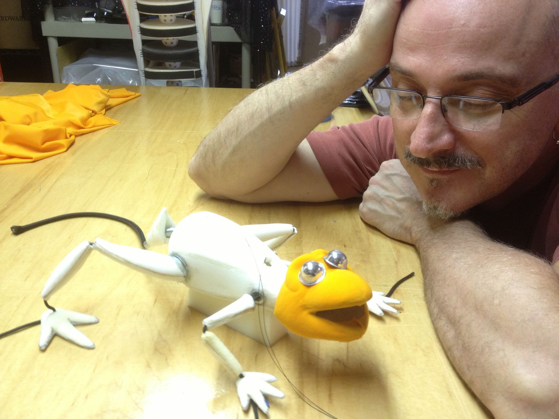A man sitting at a table with a puppet on it