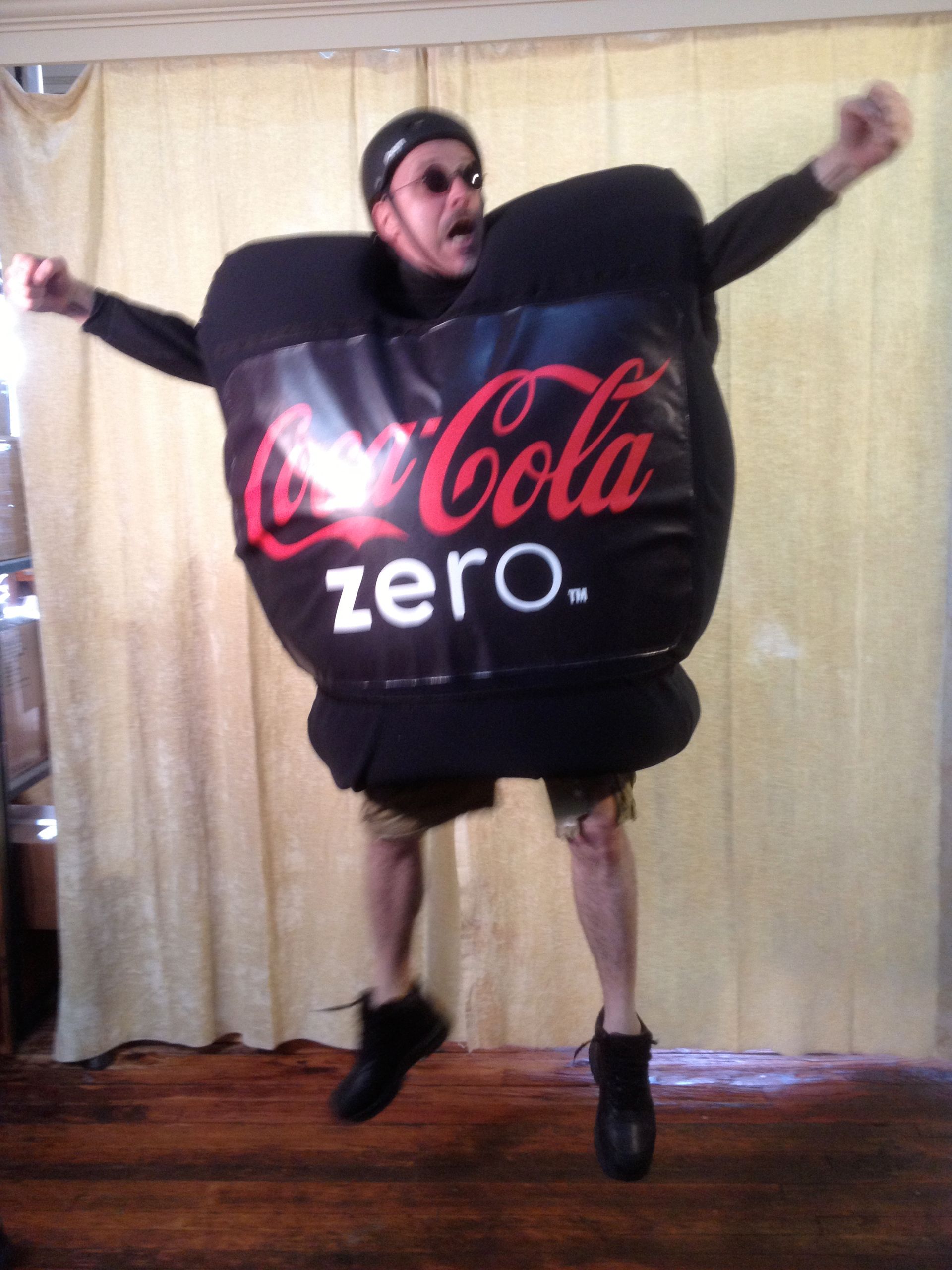A man in a coca cola zero costume jumps in the air