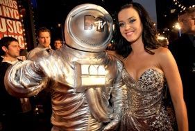 A woman in a dress is standing next to a statue of an astronaut.