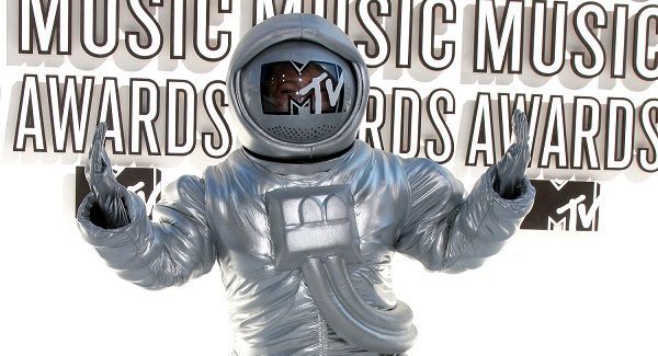 A man in a space suit is standing in front of a sign that says music music music awards