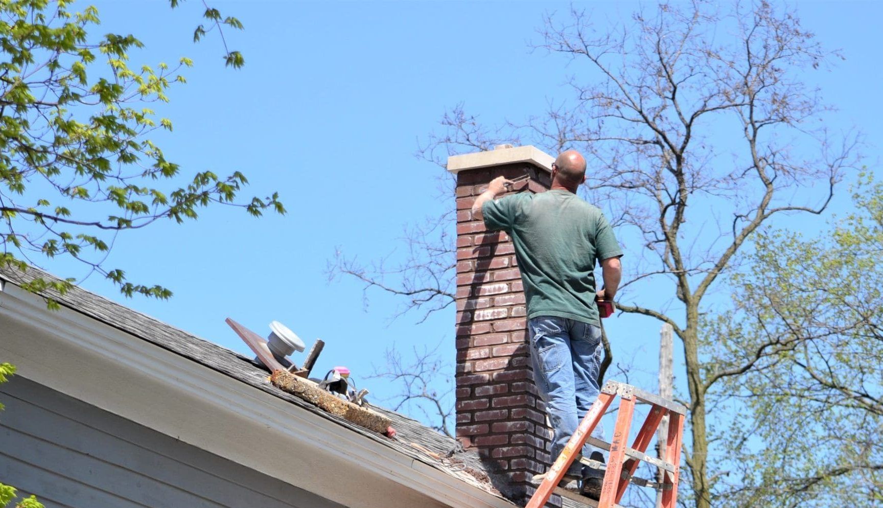 A person performing a chimney maintenance on the rooftop.