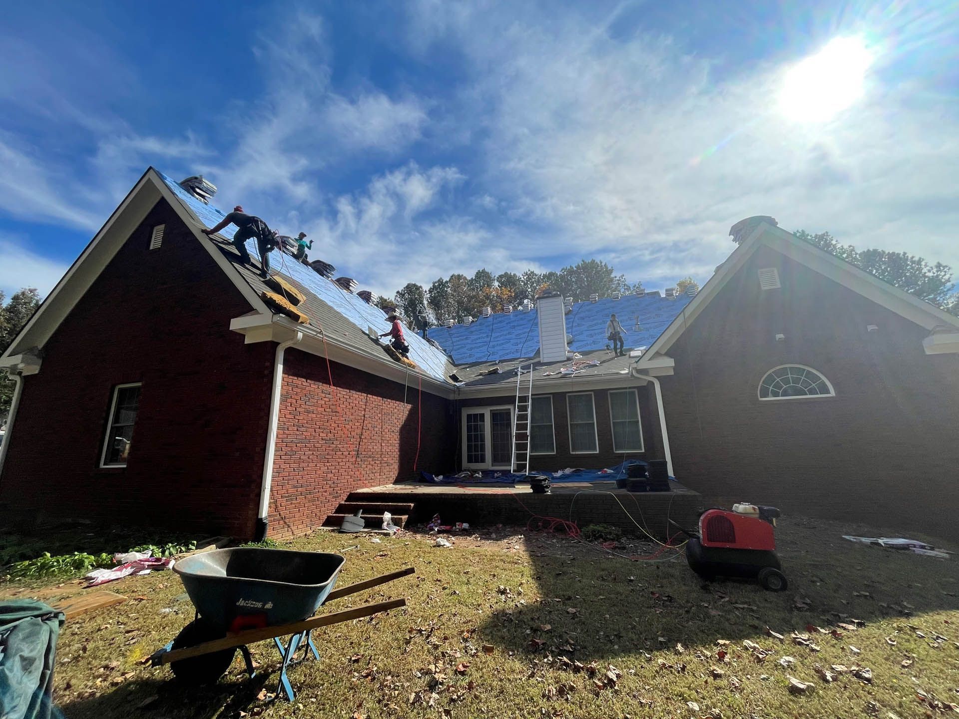 A house with a wheelbarrow in front of it is being remodeled.