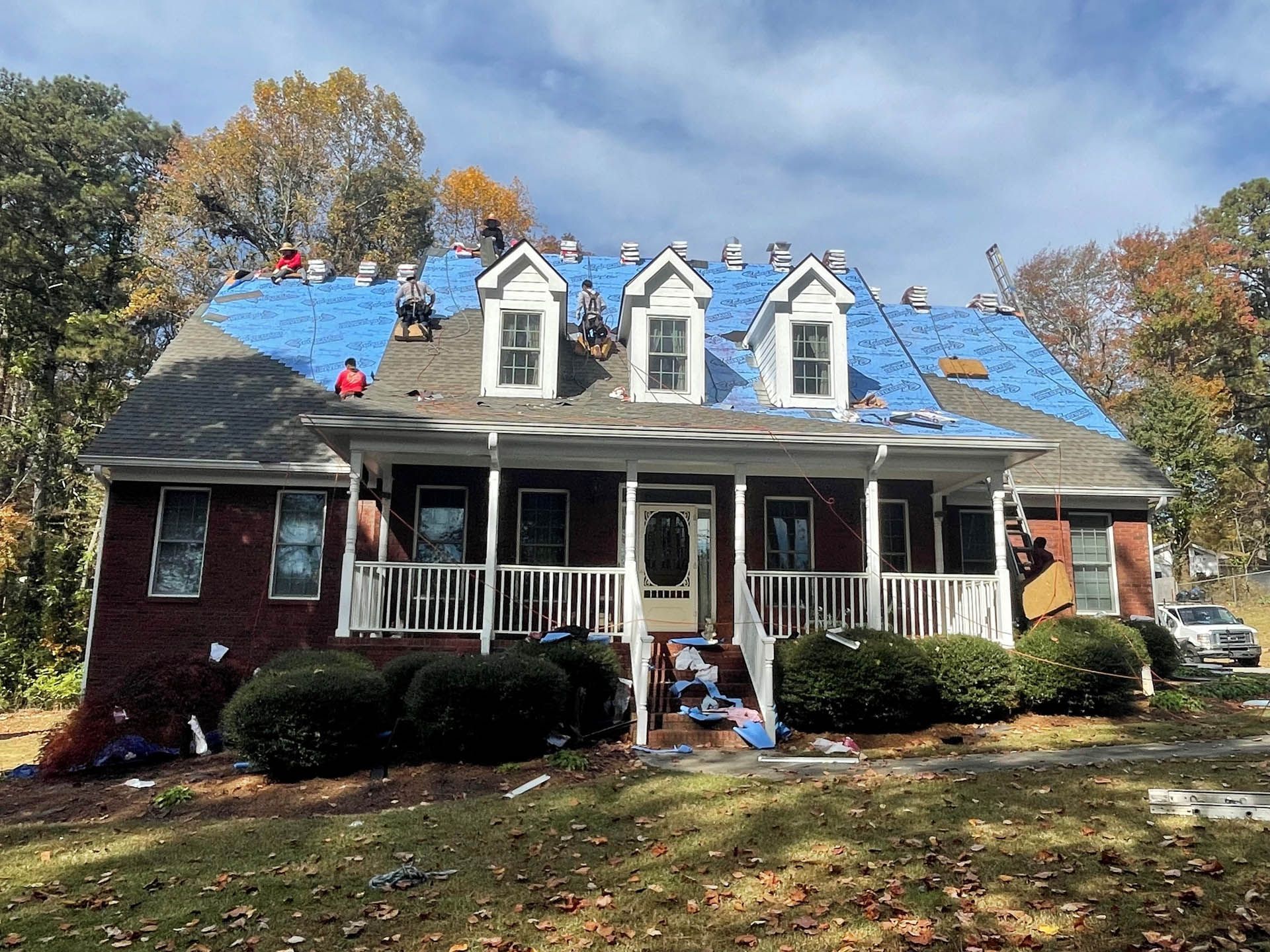 A large house with a blue roof is being remodeled.