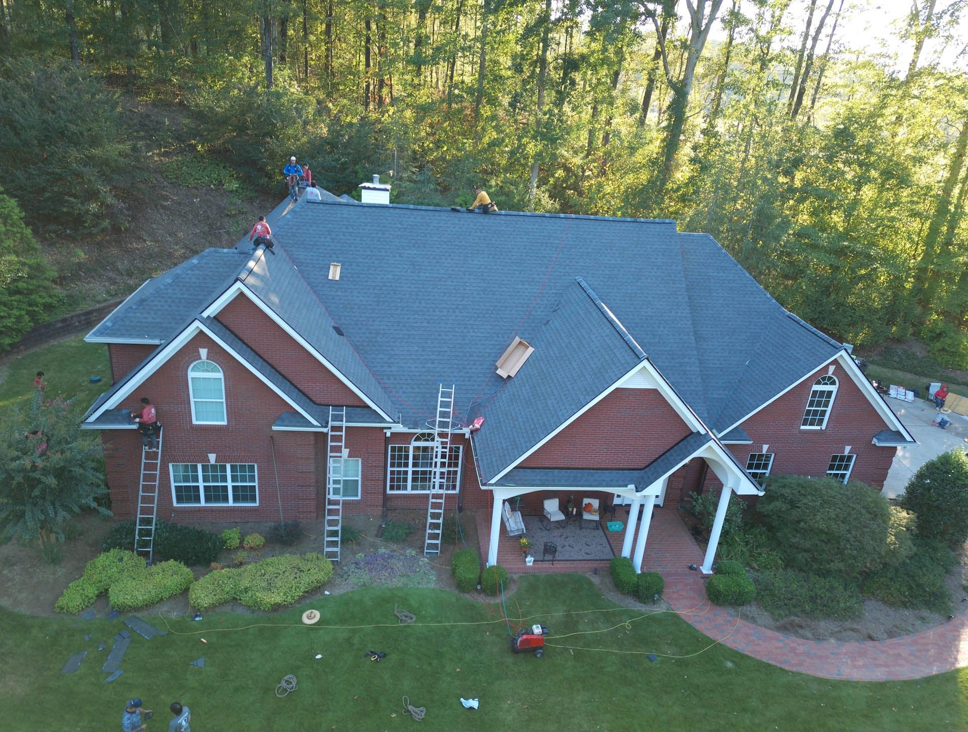 An aerial view of a large brick house with a blue roof